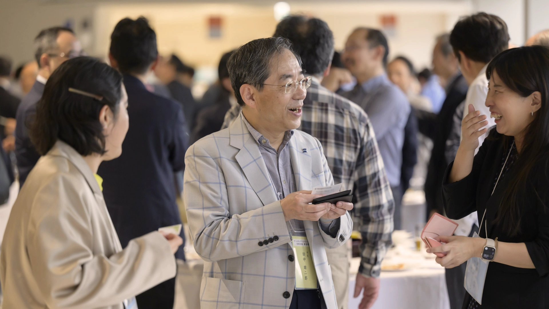 全体交流会で参加者と談笑する田中学長